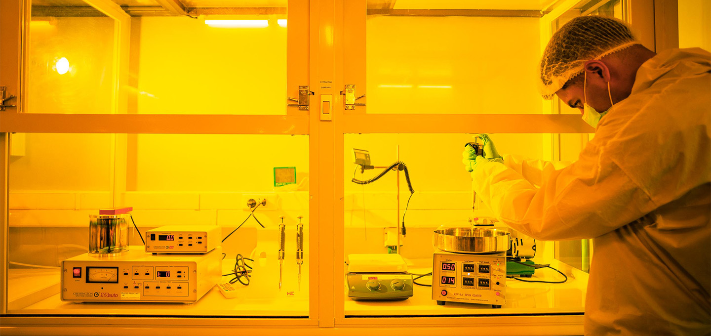 Researcher working in a laboratory under yellow lighting with equipment.